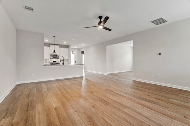 unfurnished living room with ceiling fan, visible vents, and light wood-type flooring