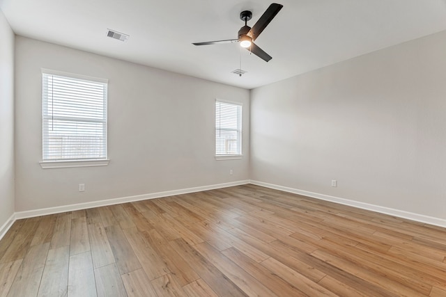 spare room with baseboards, a ceiling fan, visible vents, and light wood-style flooring