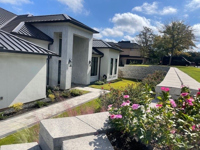exterior space with a standing seam roof, fence, stucco siding, and metal roof