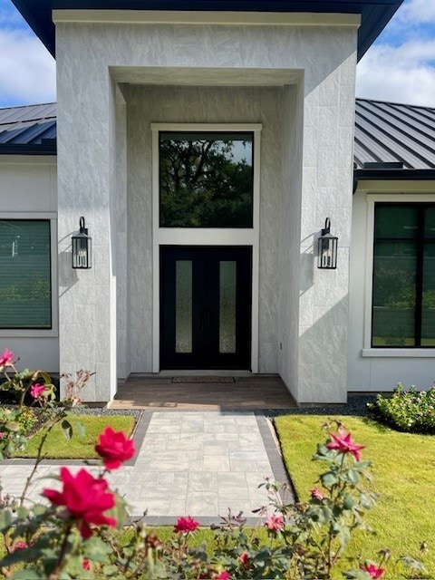 view of exterior entry with a standing seam roof, metal roof, and stucco siding