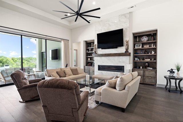 living area with visible vents, dark wood-style flooring, built in features, a fireplace, and a high ceiling