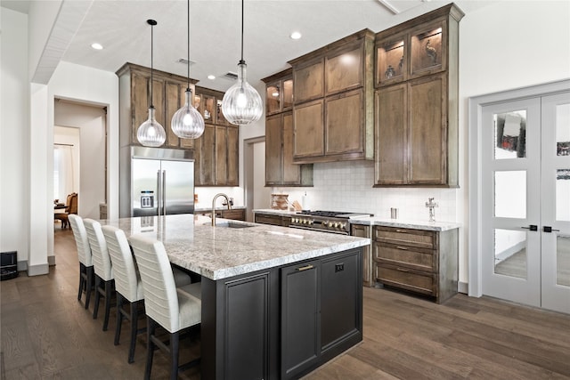 kitchen featuring dark wood-type flooring, a sink, stainless steel built in fridge, and tasteful backsplash