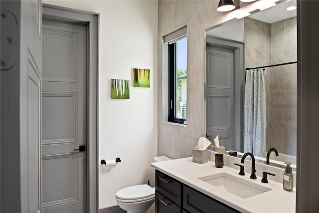 full bathroom with toilet, plenty of natural light, tiled shower, and vanity