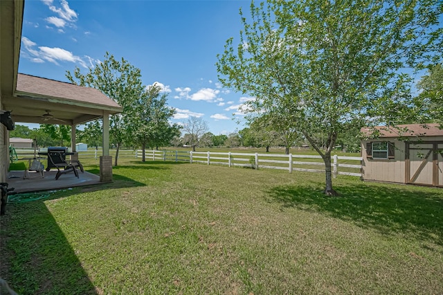 view of yard featuring fence, an outbuilding, a ceiling fan, and a storage shed
