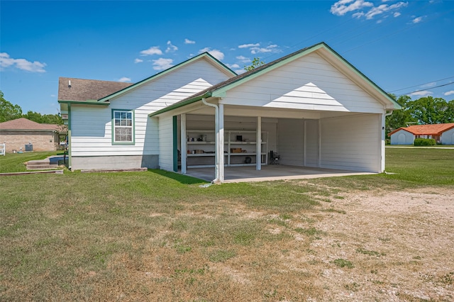 rear view of house featuring a carport and a yard