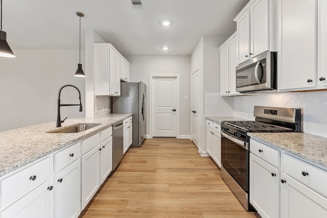 kitchen featuring white cabinets, light wood-style flooring, a sink, and appliances with stainless steel finishes