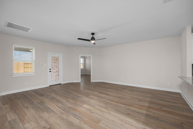unfurnished living room with baseboards, wood finished floors, visible vents, and ceiling fan