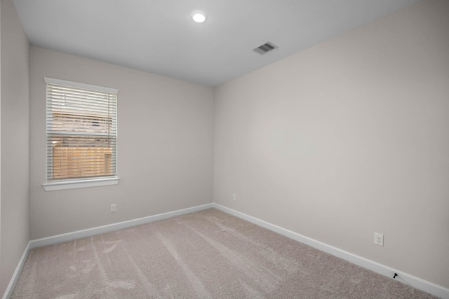 empty room featuring visible vents, baseboards, and light carpet