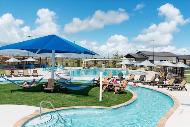 pool with a lawn, fence, and a patio area