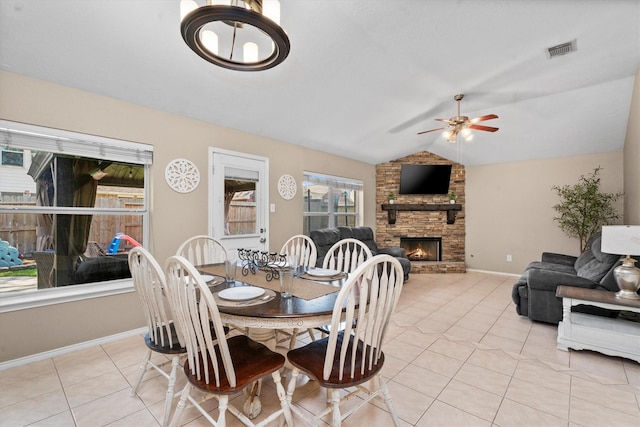 dining room with vaulted ceiling, visible vents, a brick fireplace, ceiling fan, and light tile patterned floors