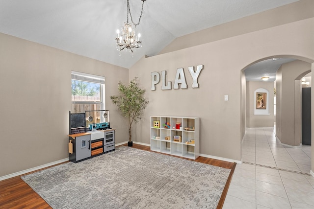 game room with lofted ceiling, baseboards, arched walkways, and light tile patterned floors