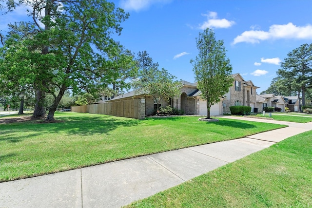 view of front facade with driveway, fence, a garage, brick siding, and a front yard