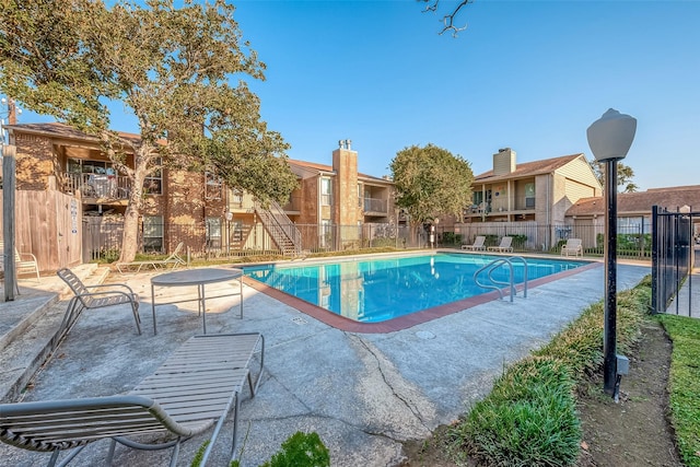 community pool with fence and a patio area