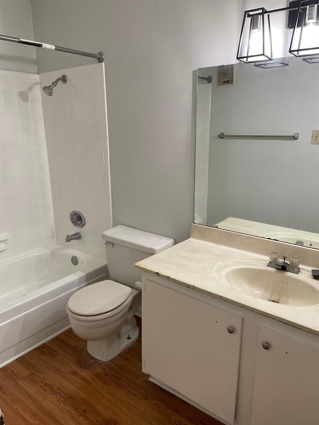 full bathroom with wood finished floors, toilet, vanity, and  shower combination