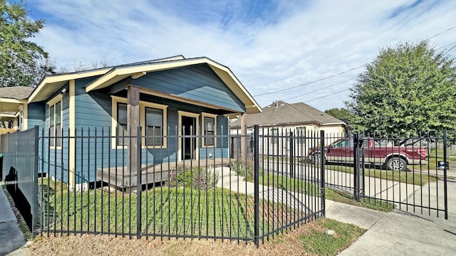 bungalow-style house featuring covered porch, a gate, and a fenced front yard