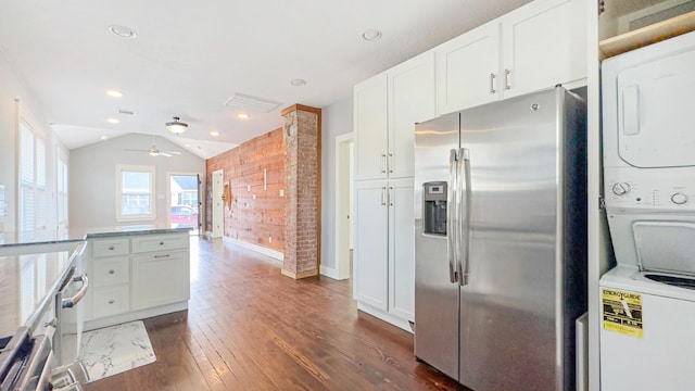 kitchen featuring dark wood finished floors, stainless steel fridge, stacked washer and dryer, and white cabinetry