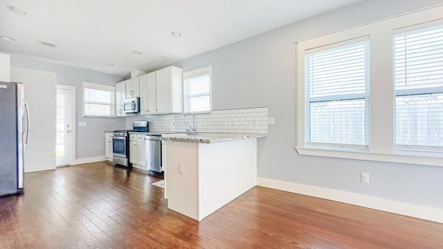 kitchen with dark wood-type flooring, a wealth of natural light, and appliances with stainless steel finishes