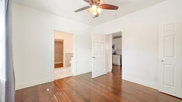 unfurnished bedroom featuring connected bathroom, baseboards, and wood finished floors