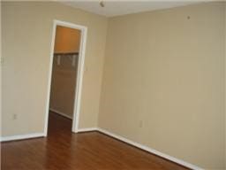 empty room with baseboards and dark wood-type flooring