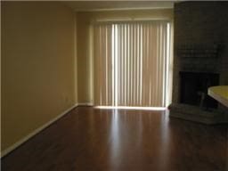 unfurnished living room featuring baseboards, wood finished floors, and a large fireplace