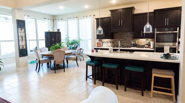 11903 Muir Groves Trl, Humble, TX 77346 - kitchen with a sink, a breakfast bar area, double oven, decorative backsplash, and light countertops