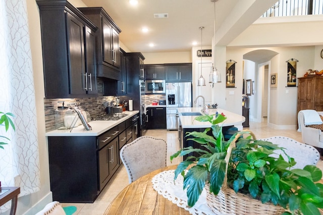 11903 Muir Groves Trl, Humble, TX 77346 - kitchen with a center island with sink, arched walkways, light countertops, appliances with stainless steel finishes, and tasteful backsplash