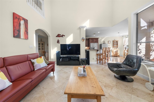 20105 Hilltop Ranch Dr, Montgomery, TX 77316 - living area featuring light tile patterned floors, arched walkways, a high ceiling, and baseboards