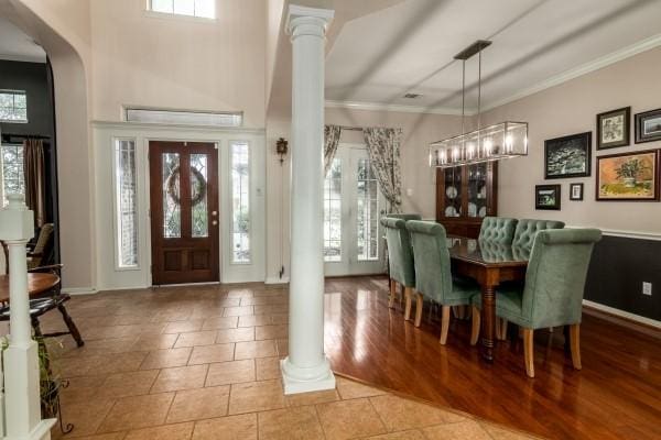 tiled entrance foyer with baseboards, a wealth of natural light, ornate columns, and crown molding