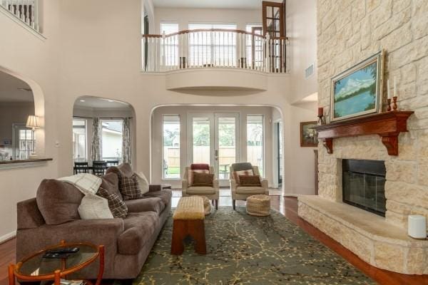 living area with arched walkways, visible vents, a high ceiling, wood finished floors, and a fireplace