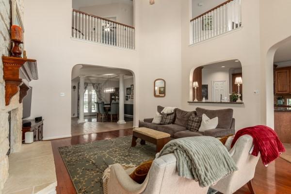 living area with arched walkways, wood finished floors, and a towering ceiling
