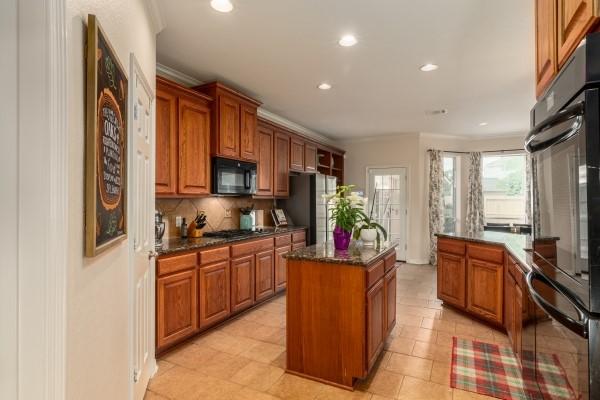 kitchen with recessed lighting, a kitchen island, decorative backsplash, black appliances, and brown cabinetry