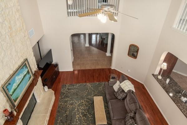 living room featuring ceiling fan, arched walkways, a glass covered fireplace, and wood finished floors