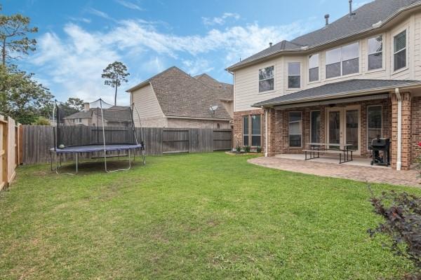 back of house featuring brick siding, a lawn, a patio, and a fenced backyard