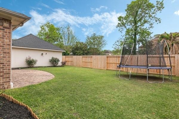 view of yard featuring a trampoline and a fenced backyard