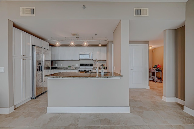 801 E Beach Dr Unit Tw1012, Galveston, TX 77550 - kitchen with stainless steel appliances, a sink, stone counters, a peninsula, and light tile patterned floors