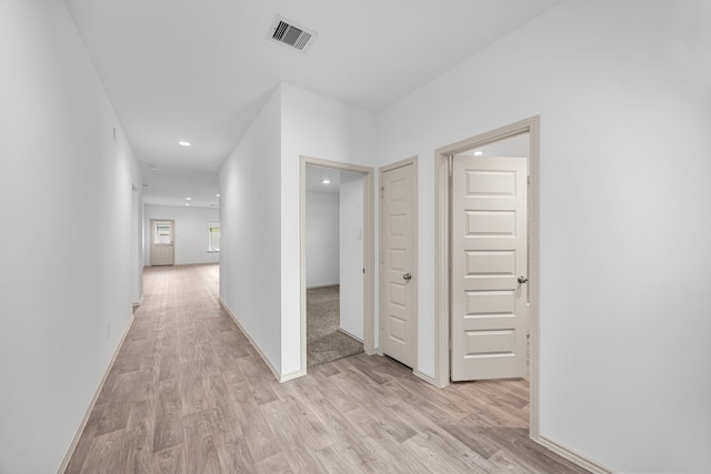 hallway with light wood-type flooring, baseboards, visible vents, and recessed lighting