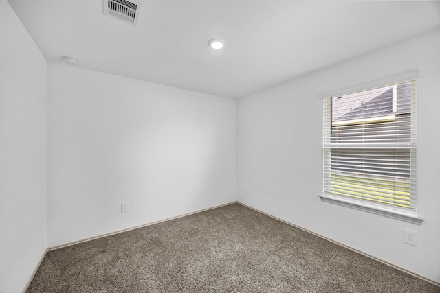empty room featuring carpet, visible vents, and baseboards