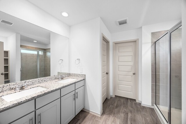 bathroom featuring a shower stall, visible vents, wood finished floors, and a sink