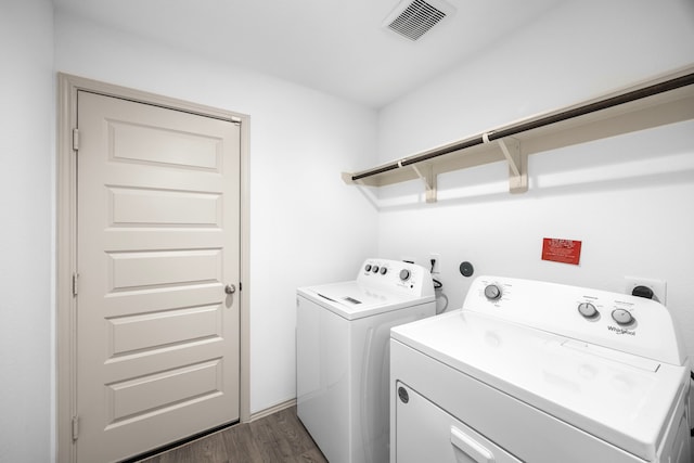 laundry room featuring washing machine and dryer, visible vents, dark wood-type flooring, and laundry area