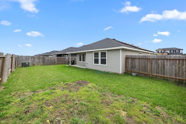 back of property featuring a lawn, a fenced backyard, and roof with shingles