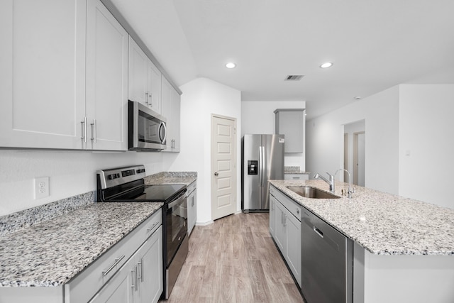 kitchen with stainless steel appliances, a sink, a center island with sink, light wood-type flooring, and visible vents