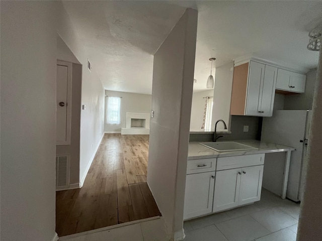 10555 Turtlewood Ct Unit 1008, Houston, TX 77072 - kitchen featuring white cabinets, a fireplace with raised hearth, visible vents, a sink, and baseboards