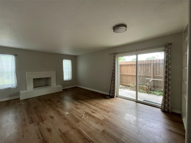 10555 Turtlewood Ct Unit 1008, Houston, TX 77072 - unfurnished living room featuring hardwood / wood-style floors, baseboards, a wealth of natural light, and a fireplace with raised hearth