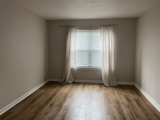 10555 Turtlewood Ct Unit 1008, Houston, TX 77072 - unfurnished room with wood finished floors, a textured ceiling, and baseboards