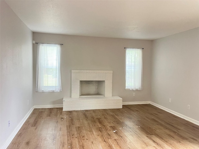 10555 Turtlewood Ct Unit 1008, Houston, TX 77072 - unfurnished living room featuring baseboards, a brick fireplace, and hardwood / wood-style flooring
