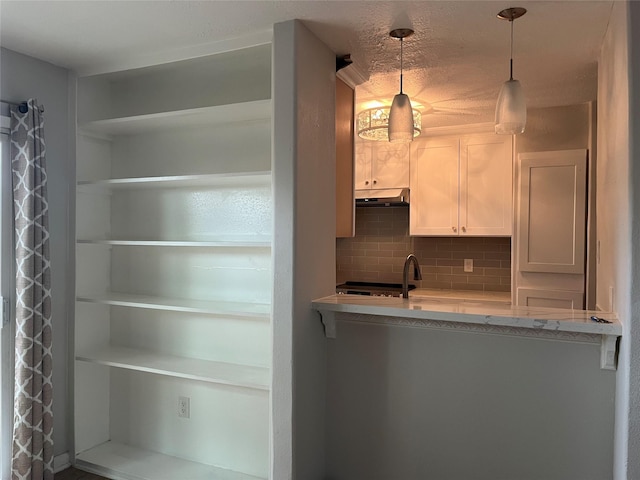 10555 Turtlewood Ct Unit 1008, Houston, TX 77072 - kitchen featuring decorative backsplash, pendant lighting, white cabinets, under cabinet range hood, and light stone countertops
