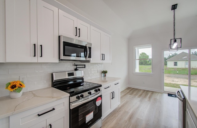1920 1st St, Hempstead, TX 77445 - kitchen featuring stainless steel appliances, vaulted ceiling, tasteful backsplash, light wood-type flooring, and hanging light fixtures