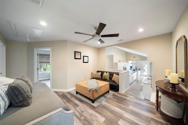 living area featuring attic access, wood finished floors, visible vents, and ceiling fan