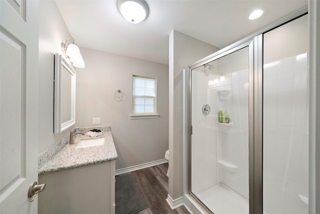 bathroom with a shower stall, wood finished floors, vanity, baseboards, and toilet