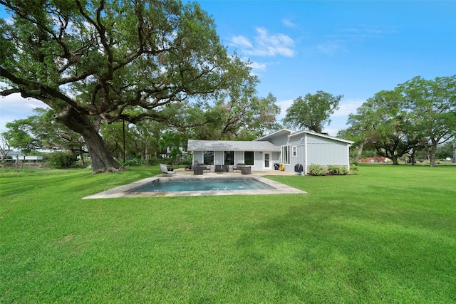 rear view of house with a patio area, an outdoor pool, and a yard